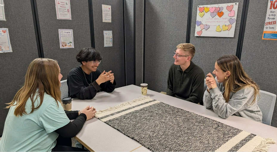 image of group of students sitting at a table together conversating.