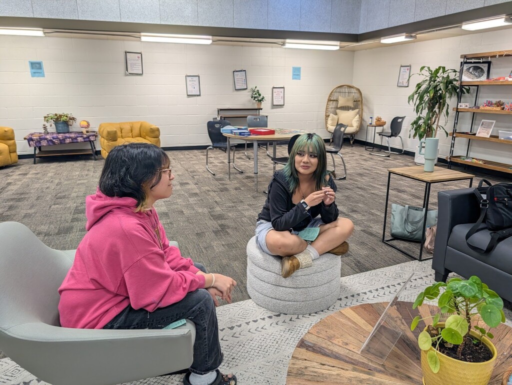 image of two female students sitting in the office conversating. 
