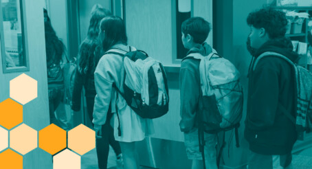 Students with backpacks standing in a line in a school hallway, with an orange honeycomb graphic overlay in the bottom-left corner.